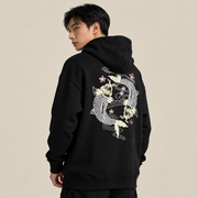 Person wearing a black Koi Embroidered Japanese Hoodie with a white floral design on the back against a plain background