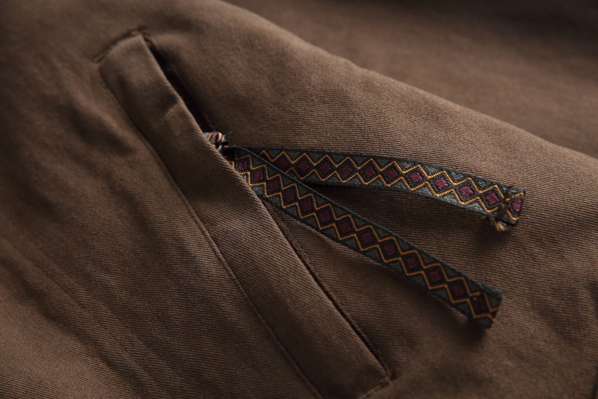 Detail of the Hagane jacket's chest zip pocket with its woven diamond-pattern ribbon pull