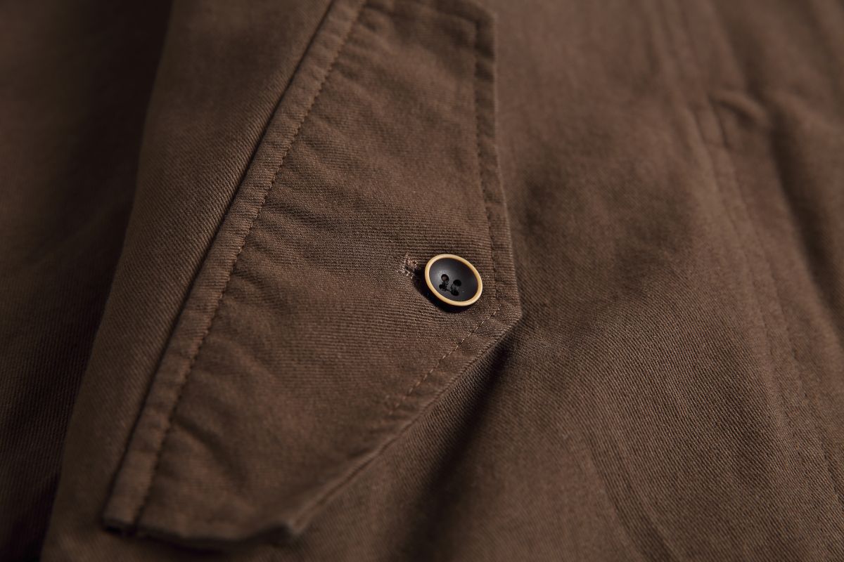 Detail of the Hagane jacket's angled flap pocket and cream-rimmed button