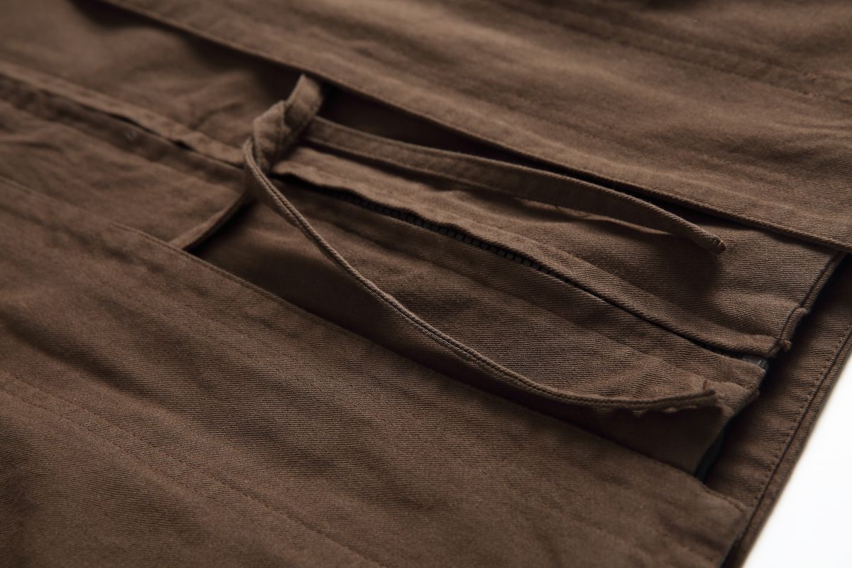 Detail of the Hagane jacket's waist drawstring threaded through the cotton twill