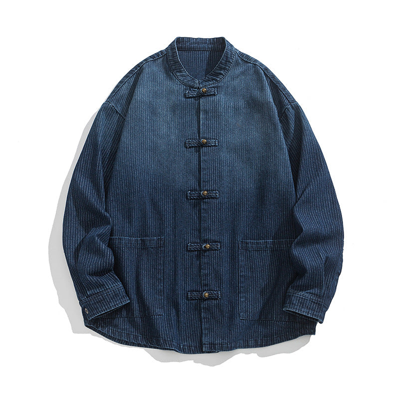 Musubi denim jacket in indigo blue laid flat, showing the stand collar, five knot-loop buttons, two hip patch pockets and the vertical slub in the wash